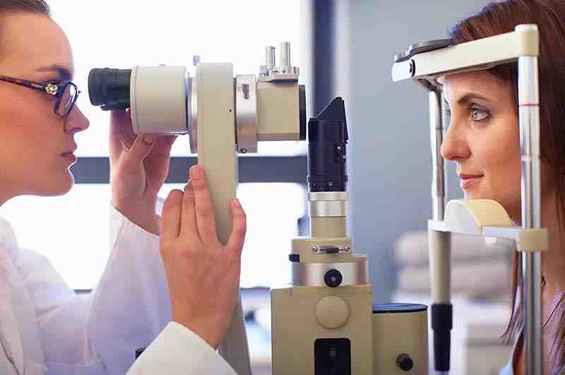 Seitenansicht einer jungen Frau bei der Augenuntersuchung durch einen Kontaktlinsenspezialisten.